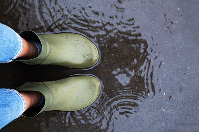 Woman wearing rubber boots standing in a puddle.