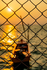 Close-up of chainlink fence against sky during sunset