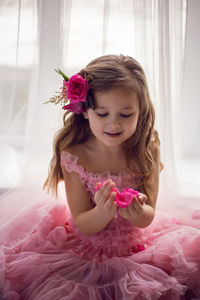 Portrait of a girl in a pink dress and a flower with a rose in her head in the studio