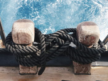 High angle view of black ropes tied on boat bollards over sea