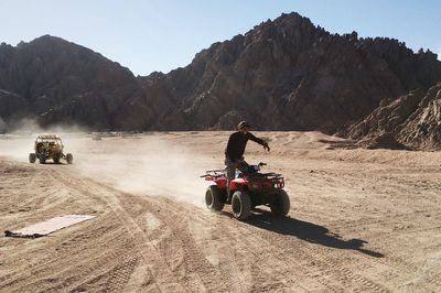 Man on motorcycle on field against clear sky