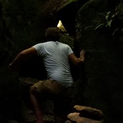 Rear view of man standing on rock at night