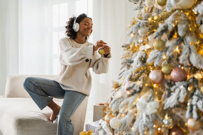 Young woman holding christmas tree at home