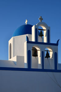 Low angle view of cross on building against clear blue sky