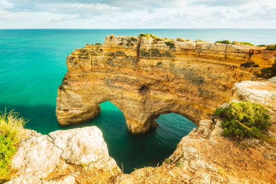 Natural arches underneath rugged cliffs, praia da marinha, algarve, portugal, europe