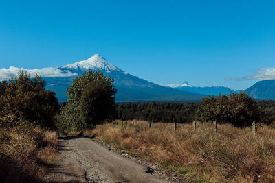 Road by mountains against clear blue sky