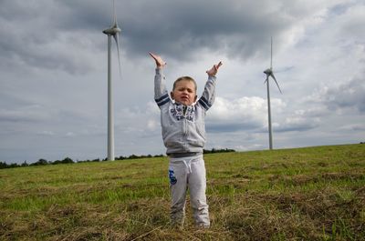 Full length of boy standing on field against sky