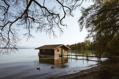 House by lake against sky