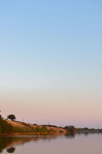 Scenic view of lake against clear sky at sunset