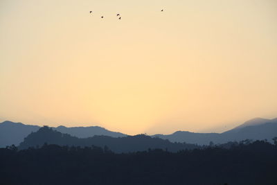 Scenic view of silhouette mountains against orange sky