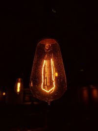 Low angle view of illuminated light bulb against black background