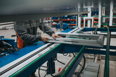 Midsection of manual worker making window frame at factory