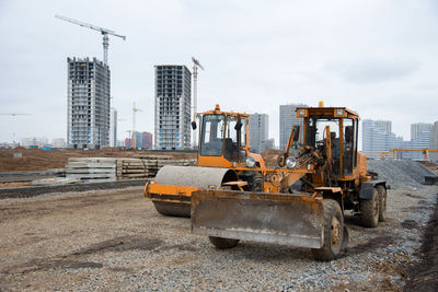 Motor grader and soil compactor at a construction site level the ground.