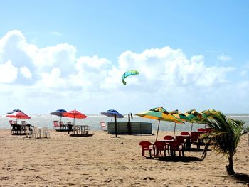 Deck chairs on beach against sky