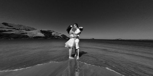 Woman with umbrella on beach against sky