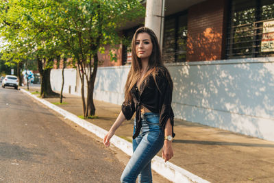 Portrait of young woman walking on road in city