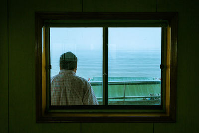 Rear view of man overlooking calm blue sea