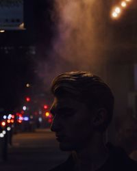 Close-up of man in illuminated city at night