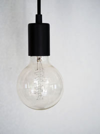 Close-up of light bulb against white wall