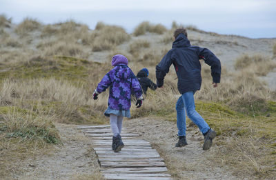 Rear view of children running on field