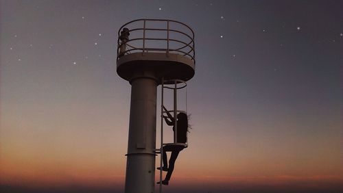 Silhouette woman climbing steps of lookout tower at night