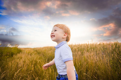 Boy standing on field against sky