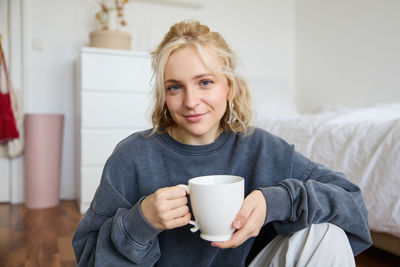 Portrait of smiling young woman using mobile phone at home