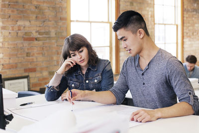 Businessman explaining plan to colleague while working in office