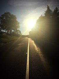 Road amidst trees against sky during sunset