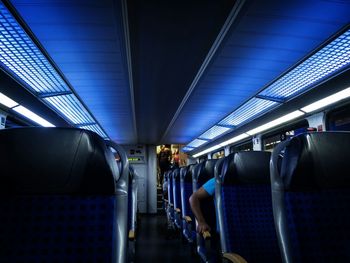 Rear view of man standing on train at illuminated railroad station