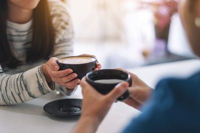 Midsection of woman holding coffee cup at cafe