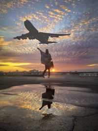 Silhouette of man flying over sea against sky