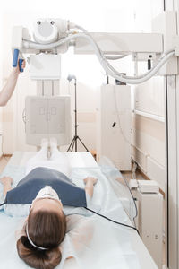 Doctor taking x-ray of patient lying on gurney. hospital radiology room. x-ray machine.