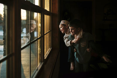 Playful boy piggybacking brother by window at home