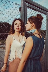 Beautiful young woman standing against fence