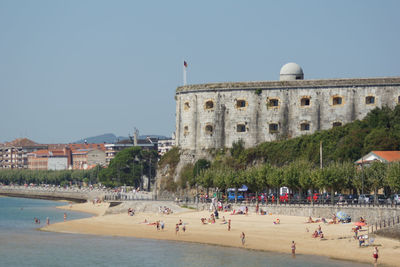 People at beach against clear sky