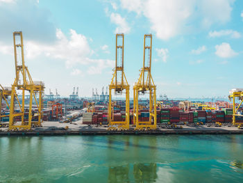 Cranes at commercial dock against sky