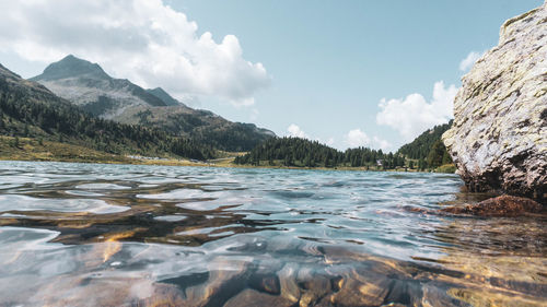 Scenic view of sea by mountains against sky