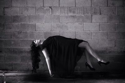 Side view of woman sitting on wall