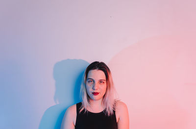 Portrait of young woman standing against wall