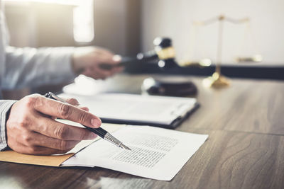 Cropped hands of lawyer working at desk in office