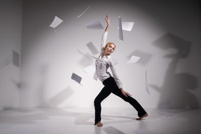 Full length of woman standing against white wall
