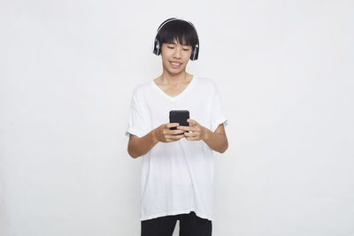 Smiling young man using mobile phone against white background