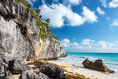 Rock formation by sea against blue sky