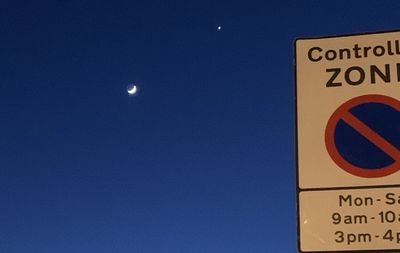 Low angle view of road sign against clear blue sky