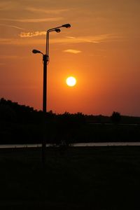 Silhouette street light against orange sky