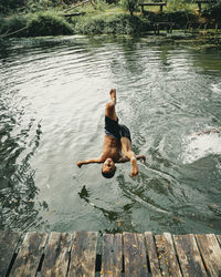 Rear view of shirtless man jumping in lake