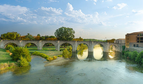 Arch bridge over river against sky