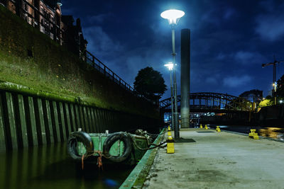 Street by illuminated buildings against sky at night