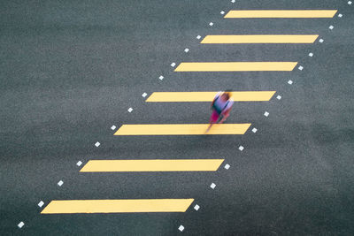 High angle blurred motion of woman walking on zebra crossing